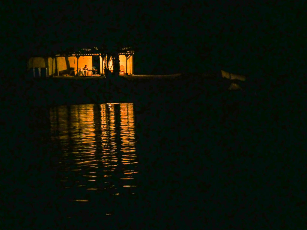 José on his porch at night, his lights powered by one solar panel.