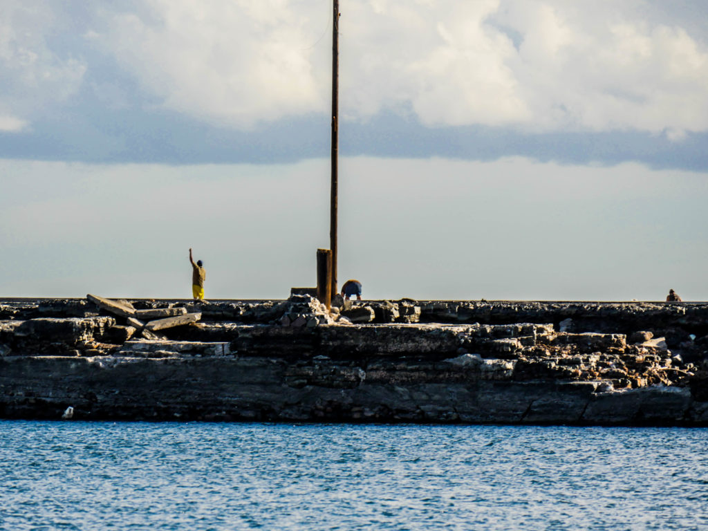  A fisherman spins his line over his head on the breakwater that protects the inner harbor, or dársena.