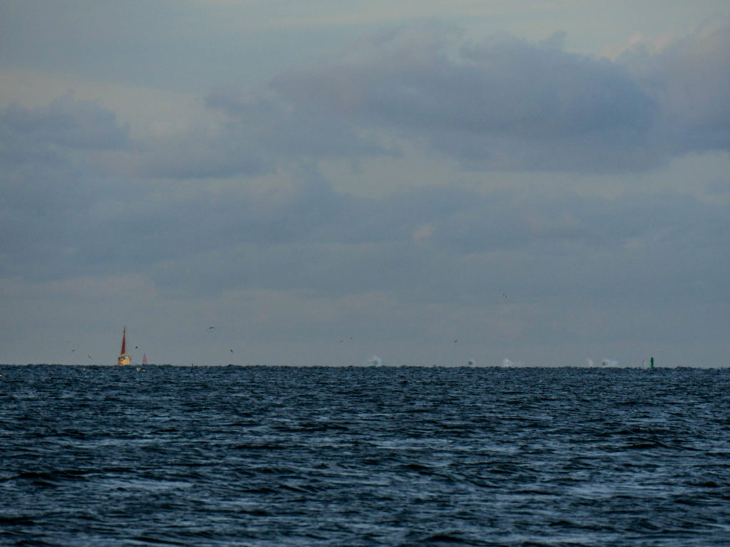 Prism entering the channel. Looking closely, two channel markers are visible in the image. Beyond the red and green markers, white spray flies from rolling breakers on the edge of the channel.