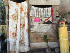 The different levels of progress for a dirt floor home: sheets for doors and windows, a propane tank for cooking (an important advancement from cooking over wood,) and an Avon beauty company sticker.