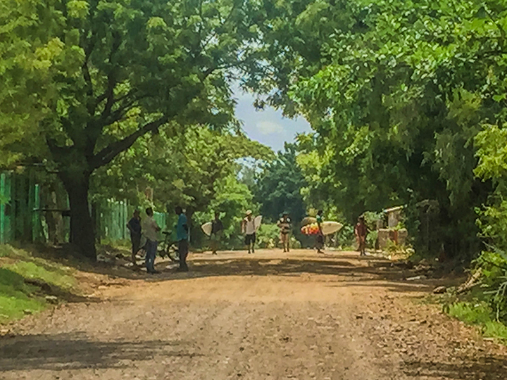 This low-resolution photo captures the laidback feeling around Aserradores: local kids walk the dirt road to the surf break, unworried and unhurried by traffic. Men stand chatting in the shade with their trusted transport, the bicycle.